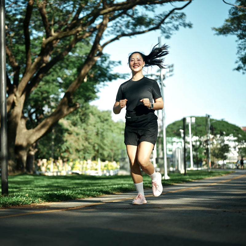 Person running on a path with trees and buildings in the background